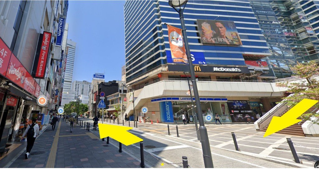 大宮駅西口デッキからアルシェ前の階段を下り、ソニックシティ方面へ進む写真。黄色い矢印で下りる方向と直進を示している