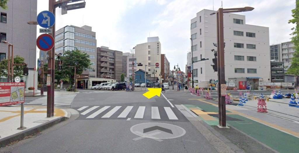 右斜め前の道へ進む写真。地面に車両進入禁止の表示があり、黄色い矢印で進む方向を示している