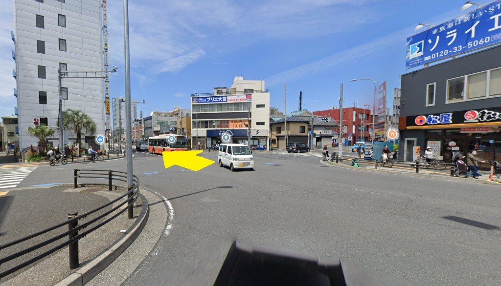 五叉路でラーメン屋どでんを右手に直進する写真。黄色い矢印で進む方向を示している
